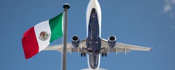 Blick von unten auf ein Passagierflugzeug mit mexikanischer Flagge daneben
