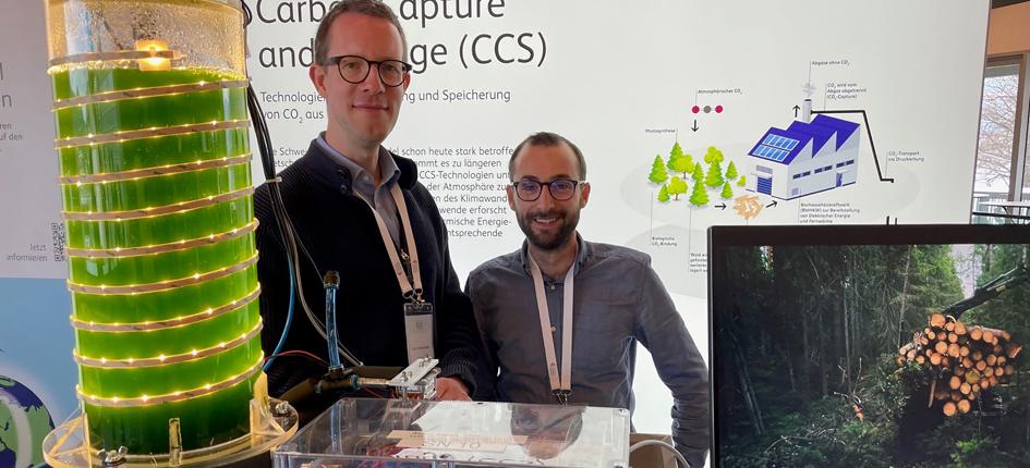 Mirko Kleingries, Head of the Competence Center Thermal Energy Systems and Process Engineering at the Lucerne University of Applied Sciences and Arts, and Master's graduate Reto Tamburini present a photobioreactor at the Swiss Energy Forum. 