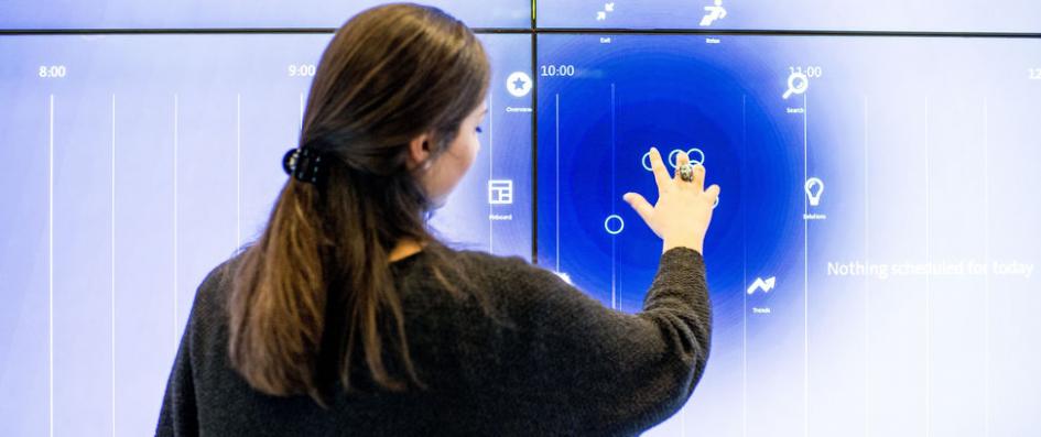 Femme devant un écran tactile de grandes dimensions.