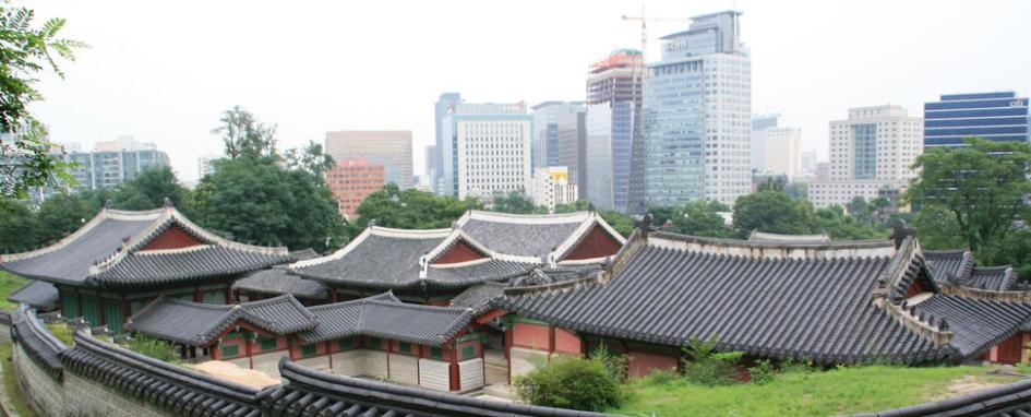Blick auf traditionelle koreanische Häuser mit modernen Hochhäusern im Hintergrund.
