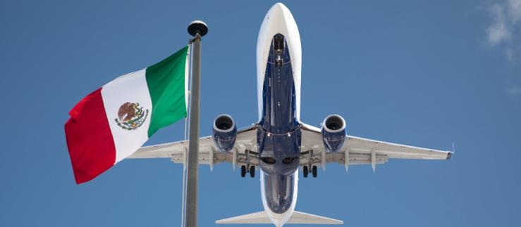 Blick von unten auf ein Passagierflugzeug mit mexikanischer Flagge daneben