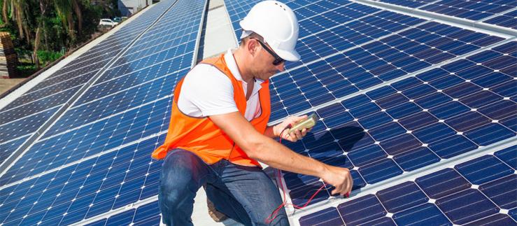 Junger Techniker überprüft Solarpanels auf einem Fabrikdach