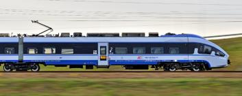 treno blu che attraversa dei campi