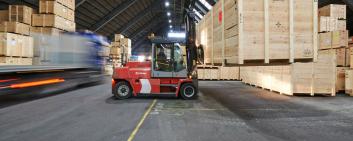 Forklift truck in warehouse lifts large wooden box