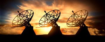 Three satelite dishes over sunset