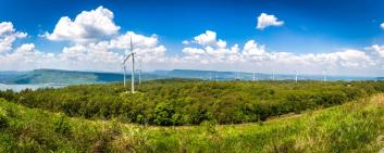 Landschaft mit vielen Windkraftanlagen auf dem weiten Grasland mit Bergen und Himmel als Hintergrund in Nakhon Ratchasima Thailand